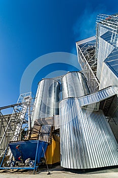 Steel factory warehouse on blue sky. Agricultural tank of fuel. exterior of elevator.