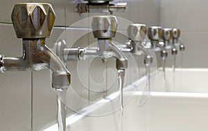 Steel faucets with water gushing in ceramic sink