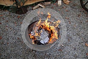 A steel fire pit with wood burning in it