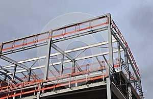 Steel frame building under construction with orange safety rail