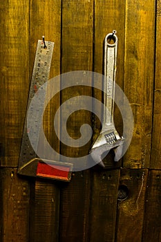 Steel framing setsquare and wrench hanging on wooden wall