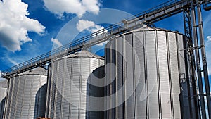 Steel Grain Silos Against Blue Sky With White Clouds