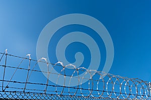 steel grating fence. coiled razor wire with its sharp steel barbs