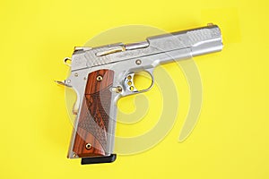 Steel gun or pistol inlaid with wood and gold isolated on a yellow background. weapon concept. protection and violence. copy space