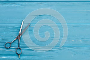 Steel hairdressing scissors on color wooden background.