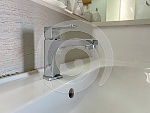 Steel hot and cold faucet at the washbasin in bathroom