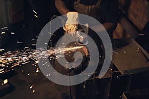 The steel industry is burning up. a man using an angle grinder while working at a foundry.