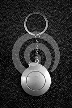 Steel key chain on dark leather background. Blank keyring in measuring tape concept