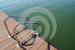 Steel ladder on off-shore planked floating dock in sunny winter