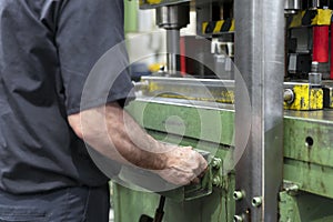 Steel Manufacturing Plant. A Worker is Placing a Piece of Metal Inside the Press. The Press is pushed Down. Metallurgy