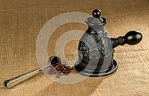 A steel measuring spoon with clay coffeepot