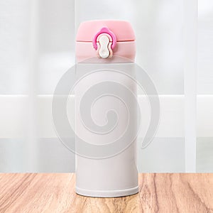 Steel mug with pink cap on kitchen backdrops. Insulated drink container