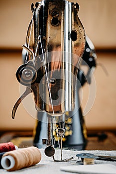 Steel needle with looper and a presser foot of old vintage hand sewing machine close-up