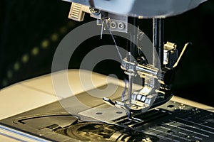 Steel needle with looper and presser foot of the sewing machine close-up