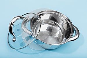 Steel pan with a transparent lid on blue background