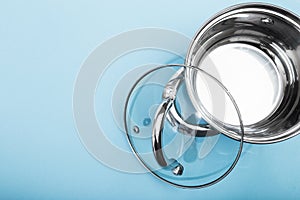 Steel pan with a transparent lid on blue background