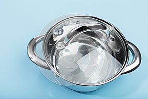 Steel pan with a transparent lid on blue background