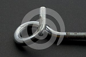 Steel pigtail screw hook on black background.
