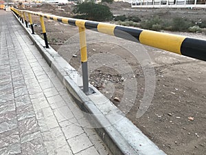 Steel pipe Guard rail painted with Yellow and Black enamel paint and acts as barrier or boundary lines of an asset owned