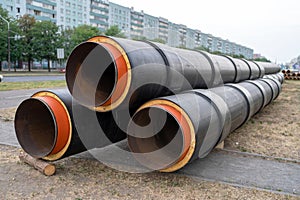 Steel pipe with heat insulation. New black insulated steel pipes at municipal construction site outdoors.