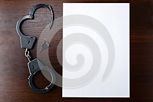 Steel police handcuffs and empty sheet of paper frame for yo