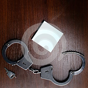 Steel police handcuffs and empty sheet of paper frame for yo