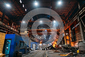 Steel production at metallurgical plant, large workshop with beam cranes and underground blast furnace