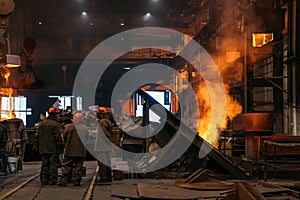 Steel production at metallurgical plant, workshop with unrecognizable workers and underground blast furnace