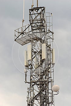 A steel radio mast (and mobile telephony and Internet transmitters) against the cloudy sky.