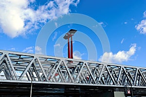 steel railway bridge closeup in perspective view. red steel tower with solar panels. blue sky