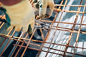 Steel reinforcement on construction site. Industrial construction worker using pliers and wire rod