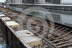 Steel reinforcing tie wire work at construction site of embankment for canal path and protecting riverbank collapse structures.