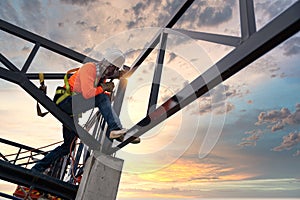 A Steel roof truss welders are working on the roof structure with safety devices to prevent fall safety at the construction site