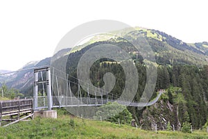 Steel rope suspenion bridge spanning the gorge in a mountain landscape