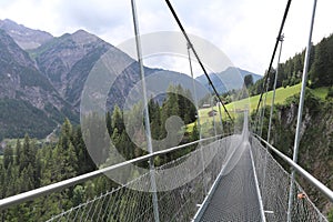 Steel rope suspenion bridge spanning the gorge in a mountain landscape