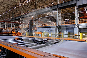 Steel sheet moving on roller conveyor in metalworking workshop