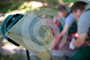 A steel shovel leaning against another against the background of workers working at the paving stones.