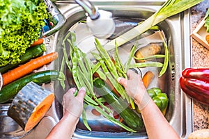 A steel sink filled with water and fresh vegetables to wash. Eat healthy to stay in shape