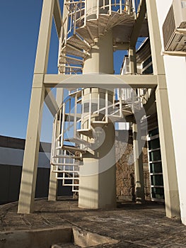 A steel spiral staircase, outdoors with blue sky background