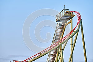 Steel structure of the highest point of a green and blue painted rollercoaster track showing the ascending and descenting parts