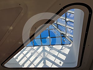 Steel structure roof ceiling made of metal and glass with blue sky background. Modern sleek shopping architecture in mall