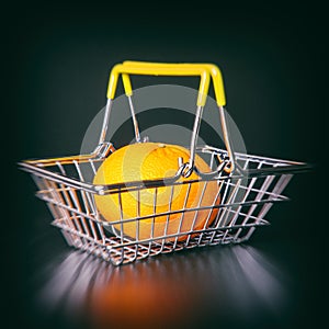 steel supermarket basket with orange on black background close-up