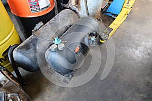 Steel tanks containing gas used to replace petrol fuel for installation in automobiles are placed on the floor in the garage.