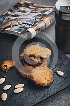 Steel thermo coffee bottle on gray concrete background with macaroons and smartphone. Tinting