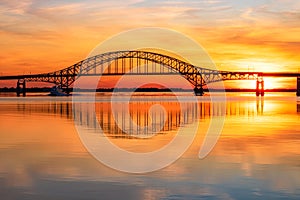 Steel tied arch bridge spanning a bay with crystal clear reflections in the water at sunset. Fire Island NY