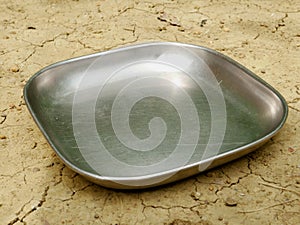 Steel water food plate kept on soil field, kitchen cutlery product image