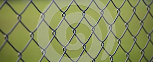 Steel wire mesh fence with green blurred background. Close up view with details.
