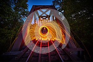 Steel wool sparks of orange at night on train track bridge