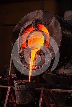 Steel worker raking furnace in an industrial foundry