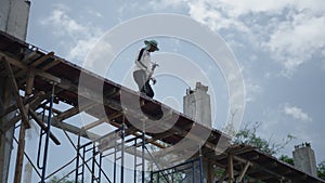 Steel Worker On Scaffold Platform Carrying Fabricated Rebars For Reinforced Concrete. low angle